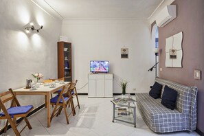A compact living space with a dining area, a sofa, a TV, and a small table with magazines. - La Casa dei Giusti by Wonderful Italy (Genova)