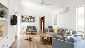 A modern living room with a sofa, chairs, a coffee table, and a dog. - Golden Sands - Pet Friendly - 2 Mins Walk to Beach (Culburra Beach)