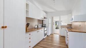 A modern kitchen with white cabinetry, a wooden countertop, and a view to the outside. - Golden Sands - Pet Friendly - 2 Mins Walk to Beach (Culburra Beach)