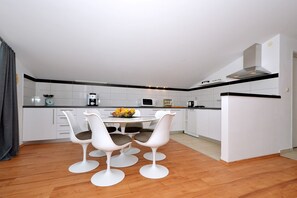 A modern kitchen with white cabinets, a wooden floor, and a dining area with white chairs and a fruit bowl. - Blue Sky 5 - apt with 3 bedrooms for 5+2 in Mastrinka, (Mastrinka)