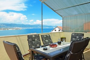 A balcony with wicker chairs and a table, overlooking a coastal view with mountains and a city in the distance. - Blue Sky 5 - apt with 3 bedrooms for 5+2 in Mastrinka, (Mastrinka)