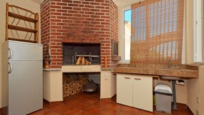 Eine kleine Küche mit Backofen, Kühlschrank und einem Fenster mit Jalousien.