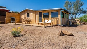 Une cabane en bois dotée d’une terrasse, de deux fauteuils et d’une table.
