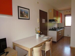 Eine kompakte Küche mit Essbereich, einem kleinen Fernseher und einem Bild an der Wand.