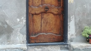 Een houten deur met decoratieve details, geplaatst in een raam met een stenen omlijsting.