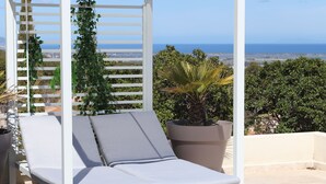 A white outdoor lounge chair with cushions, a white pergola, and a potted plant. - Villa with pool, sea view (Borgo)