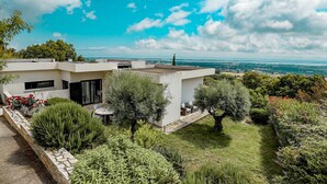 A modern house with a flat roof, a patio with outdoor furniture, and a well-maintained garden. - Villa with pool, sea view (Borgo)