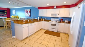 A modern kitchen with white cabinets, a granite countertop, a microwave, an oven, and a refrigerator. - Ocean's Edge 403-Oceanfront 9th St, Free WiFi, Elev, W/D, AC (Ocean City)