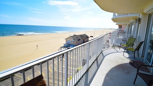 A balcony with a view of the beach, a lifeguard tower, and a building with a sloped roof. - Ocean's Edge 403-Oceanfront 9th St, Free WiFi, Elev, W/D, AC (Ocean City)