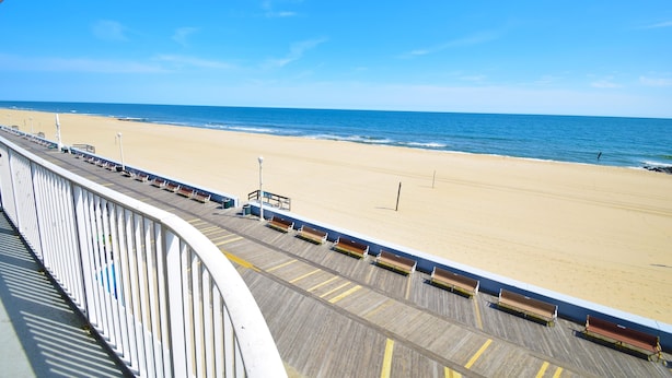 A beach view from a balcony with a wooden deck and benches. - Ocean's Edge 403-Oceanfront 9th St, Free WiFi, Elev, W/D, AC (Ocean City)