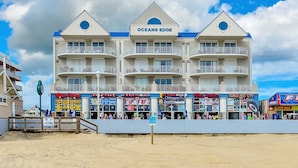 A beachfront hotel with multiple balconies and a variety of shops on the ground floor. - Ocean's Edge 403-Oceanfront 9th St, Free WiFi, Elev, W/D, AC (Ocean City)
