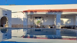 Un bâtiment moderne doté d’une piscine, d’un patio couvert et d’un mur en pierre.