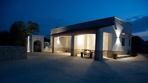 Un bâtiment moderne doté d’un patio couvert, de murs en pierre et d’un banc.