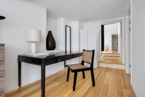 A modern room with a black desk, a chair, a lamp, and a large vase.