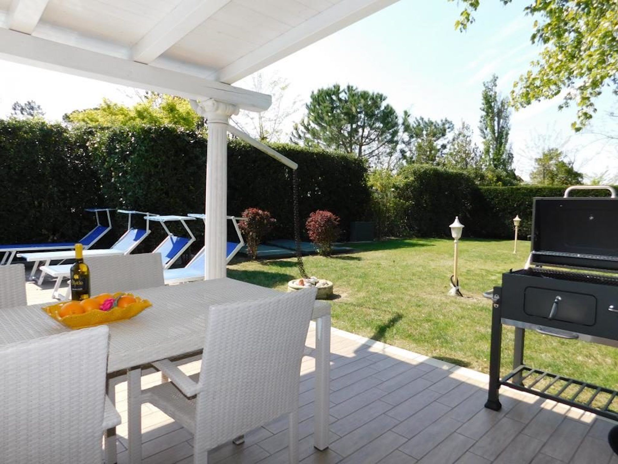 Un patio con mesa, sillas, una parrilla y un área de piscina.