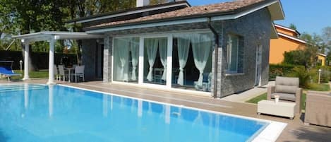Una casa moderna con piscina, patio cubierto y jardín.