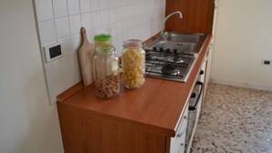 Eine Küche mit Holzarbeitsplatte, einem Gasherd und zwei Pastagläsern.
