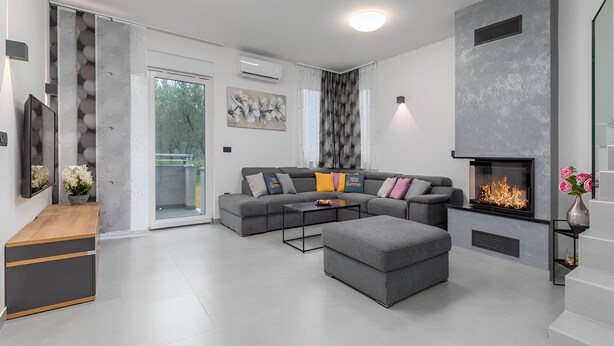 A modern living room with a grey sectional sofa, a fireplace, and a staircase. - Villa D Pula 3-bedrooms Luxury Accomodation (Pula)