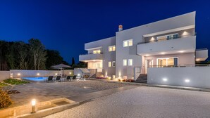 A modern multi-story house with a swimming pool, outdoor seating, and a well-lit entrance. - Villa D Pula 3-bedrooms Luxury Accomodation (Pula)