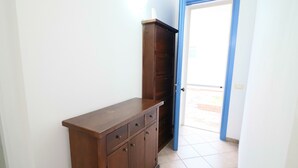Een gang met een houten kast en een deur die naar buiten leidt.