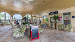 Un espace café en plein air avec des tables et un menu écrit à la craie sur un tableau noir.