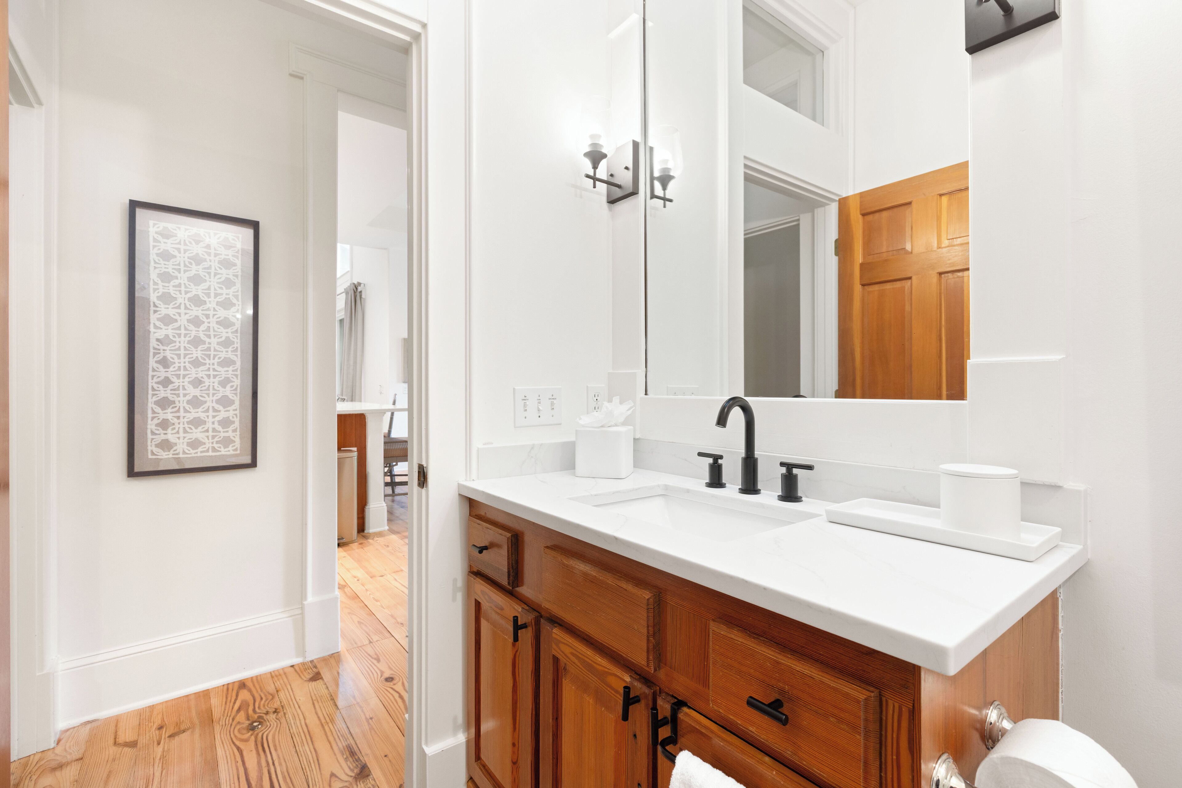 Une salle de bain avec un meuble-lavabo blanc, un grand miroir et un placard en bois.