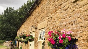 A stone building with hanging flower baskets and a door. - Luxury, Self-contained Country Cottage With View (Scarborough)