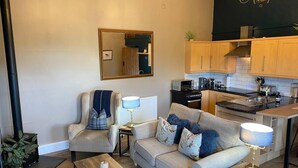 A compact living space with a sofa, armchair, coffee table, and a kitchenette area. - Luxury, Self-contained Country Cottage With View (Scarborough)