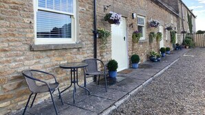 A row of stone buildings with a row of outdoor seating and hanging flower baskets. - Luxury, Self-contained Country Cottage With View (Scarborough)