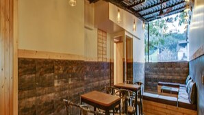 A rustic interior with wooden walls, a stone floor, and a seating area with a bench and tables. - We Stay - Andheri (Mumbai)