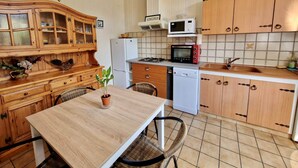 Une cuisine de taille réduite, avec des meubles de rangement en bois, une table à manger et un four à micro-ondes.