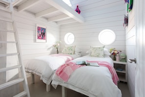 A bedroom with two beds, a ladder, a window, and a door.