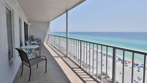 Un balcón con vista a la playa, que incluye una mesa, sillas y barandilla.