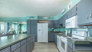 Una cocina con gabinetes grises, un refrigerador blanco, una estufa y un microondas.