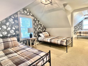 Une chambre avec deux lits, une table de chevet, une lampe et une fenêtre donnant sur un beau paysage.