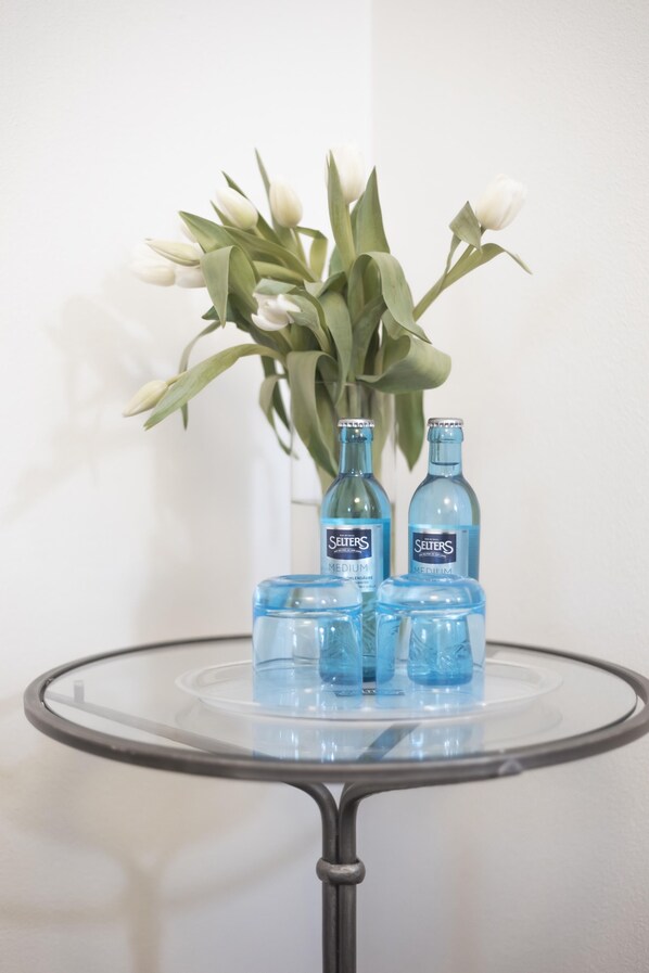 Una mesa de vidrio con tres botellas de Seiters Medium y un jarrón con tulipanes blancos.