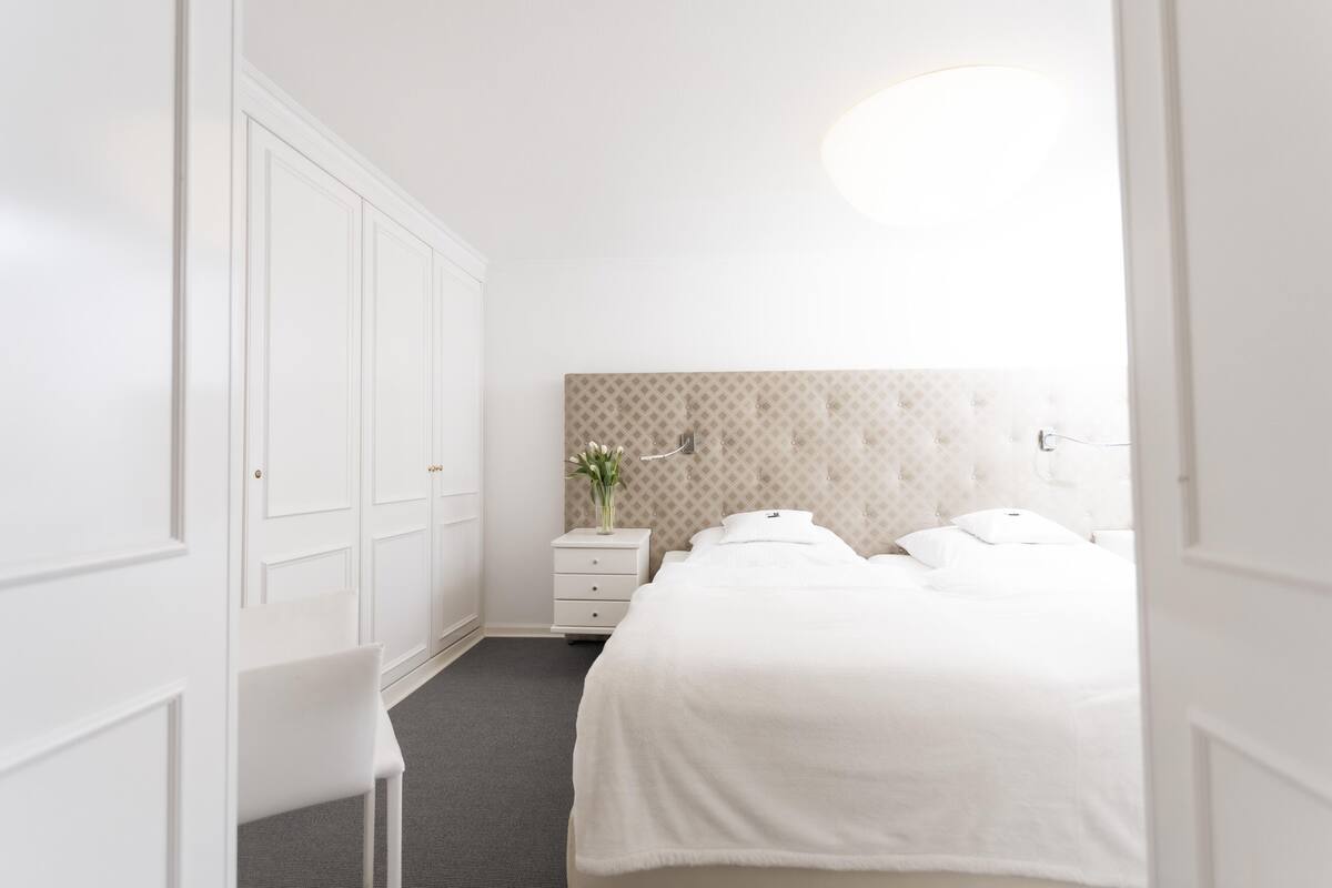 A bedroom with a bed, a nightstand, a chair, and a wardrobe.