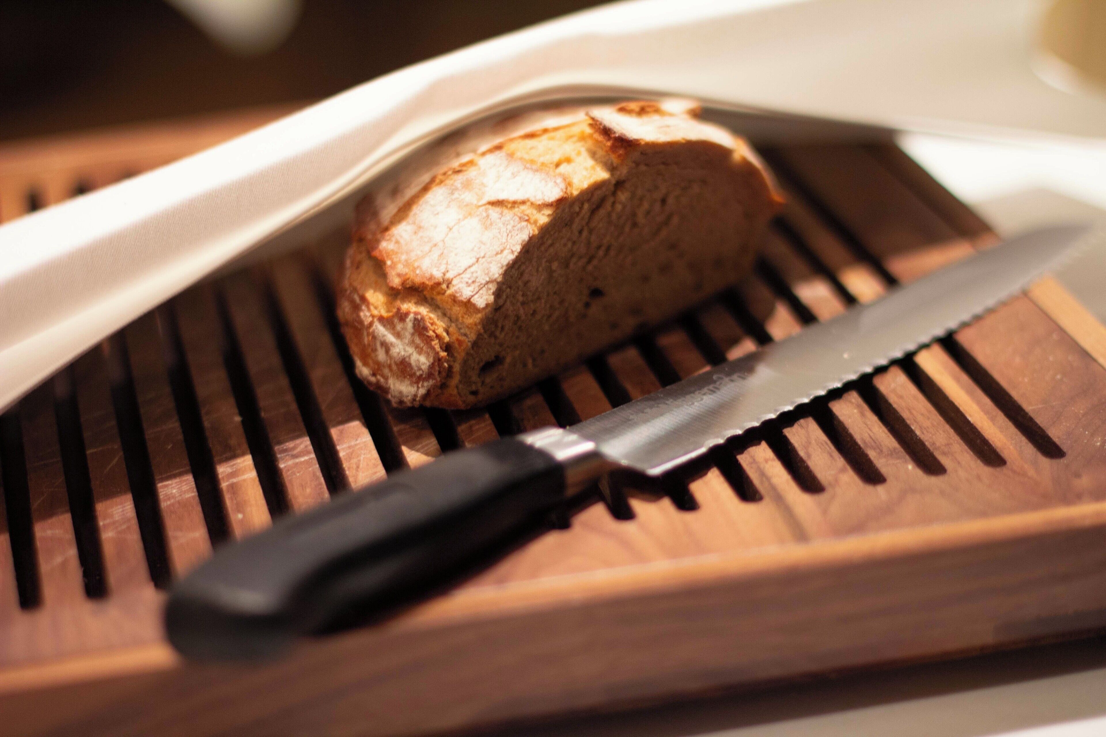 Une miche de pain sur une planche à découper en bois, avec un couteau.