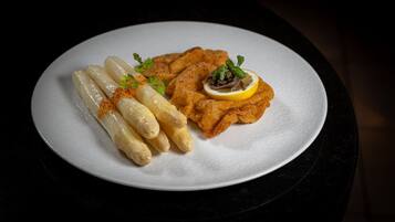 Un plato con milanesa, espárragos y una rodaja de limón.