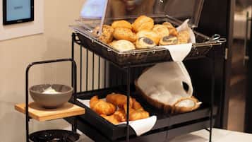 A buffet with various baked goods and a bowl of soup.