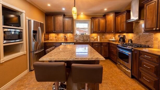 Una cocina moderna con encimeras de granito, electrodomésticos de acero inoxidable y armarios de madera.