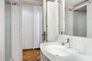 Een moderne badkamer met een wit wastafelmeubel, een grote spiegel en een houten vloer.
