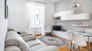 A modern living room with a sofa, a dining table with chairs, a TV, and a decorative rug. - Bright apartment near Villa Borghese (Roma)