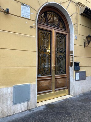 A yellow building with a large, ornate metal gate and a wooden door. - Bright apartment near Villa Borghese (Roma)