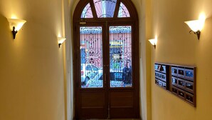A hallway with a wooden door featuring stained glass, flanked by wall-mounted light fixtures and a display of framed pictures. - Bright apartment near Villa Borghese (Roma)