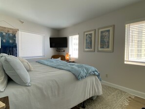 Een slaapkamer met een bed, een televisie en twee afbeeldingen in lijsten aan de muur.