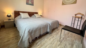 Ein Schlafzimmer mit einem Bett, Nachttischlampen, einem Sessel, Holzboden, Deckenleuchte, Wandbild und Wanddeko.