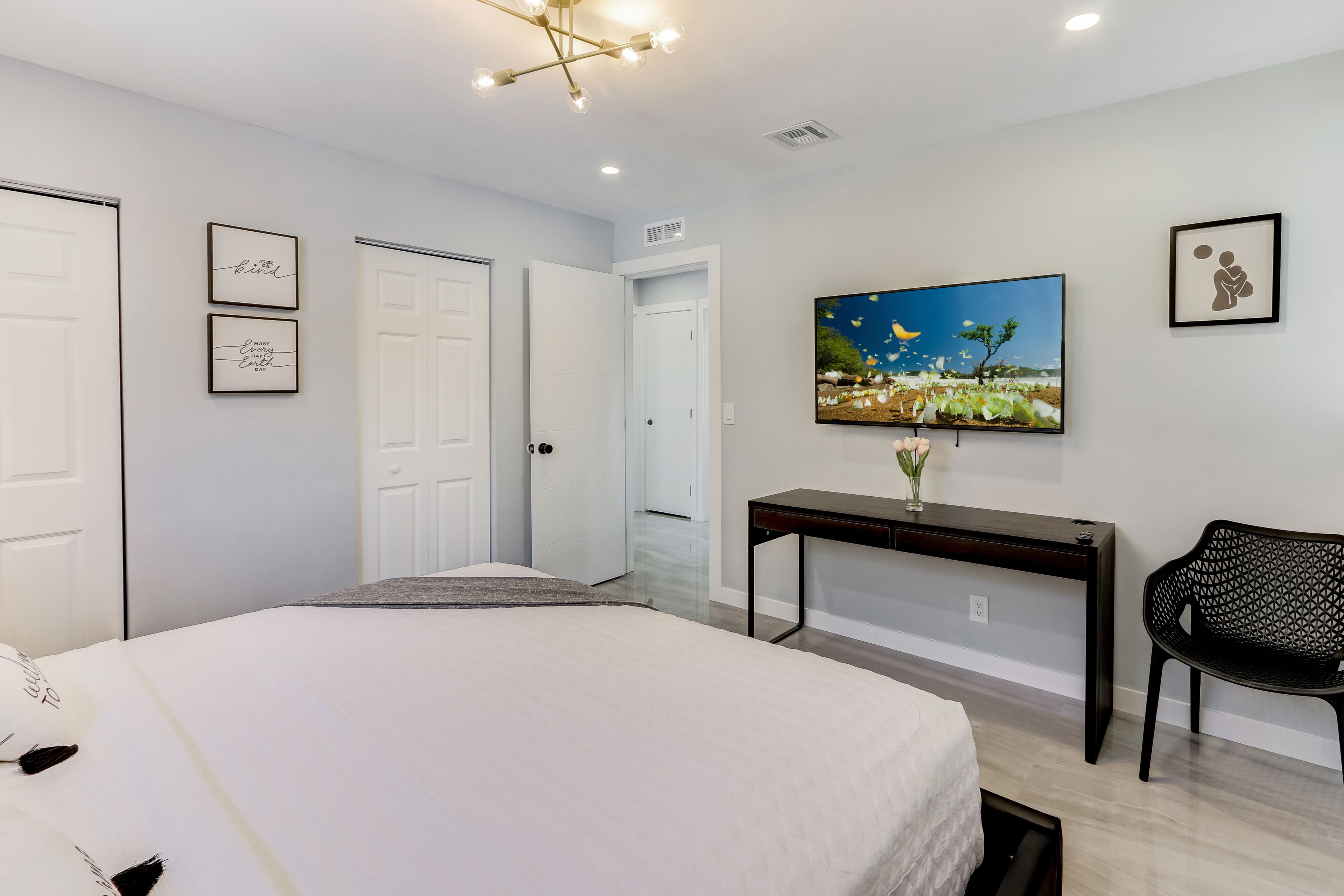 A bedroom with a bed, a desk, a chair, and a television.