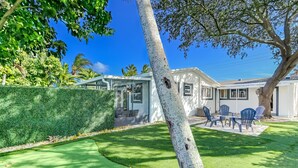 Une maison moderne dotée d’un porche vitré, d’une pelouse bien entretenue et de mobilier d’extérieur.