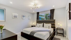 Une chambre moderne avec un grand lit, des tables de chevet, un bureau et une fenêtre avec des rideaux.